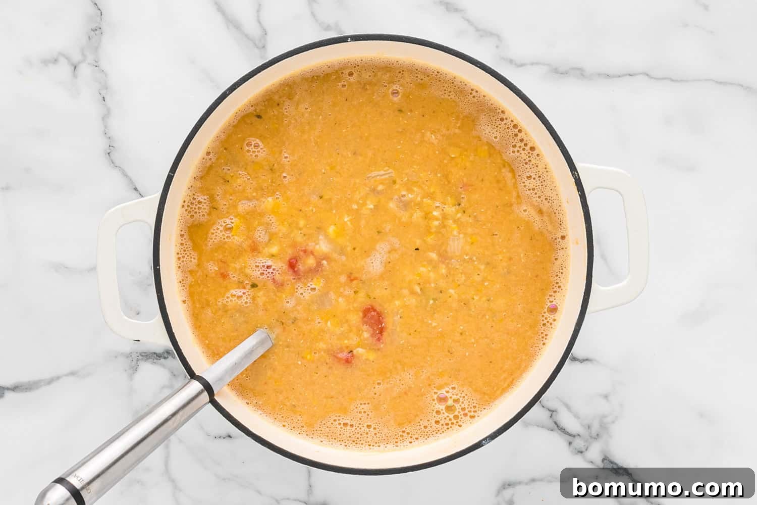 A ladle scooping out a generous portion of the finished red lentil soup, showcasing its rich and comforting texture.