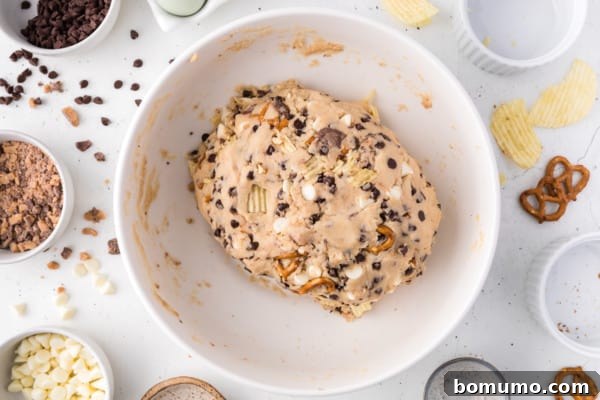 A perfectly formed ball of kitchen sink cookie dough in a mixing bowl, ready for baking.