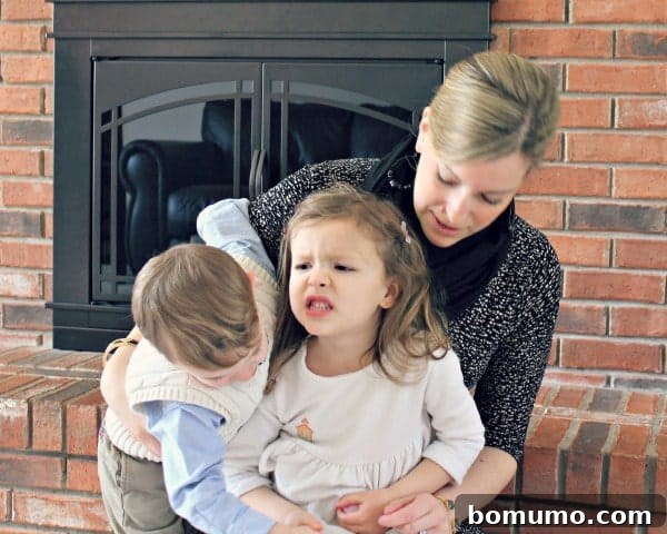 A mom with two toddlers in a playful, perhaps chaotic, moment.