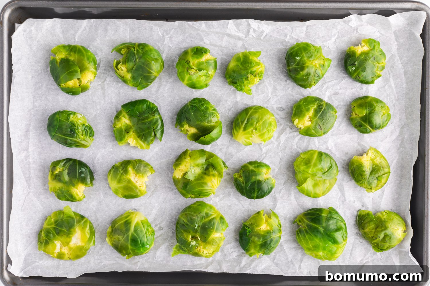 Crispy Roasted Brussels Sprouts 7 Whole Brussels sprouts on a sheet pan, after being smashed down and flattened slightly.