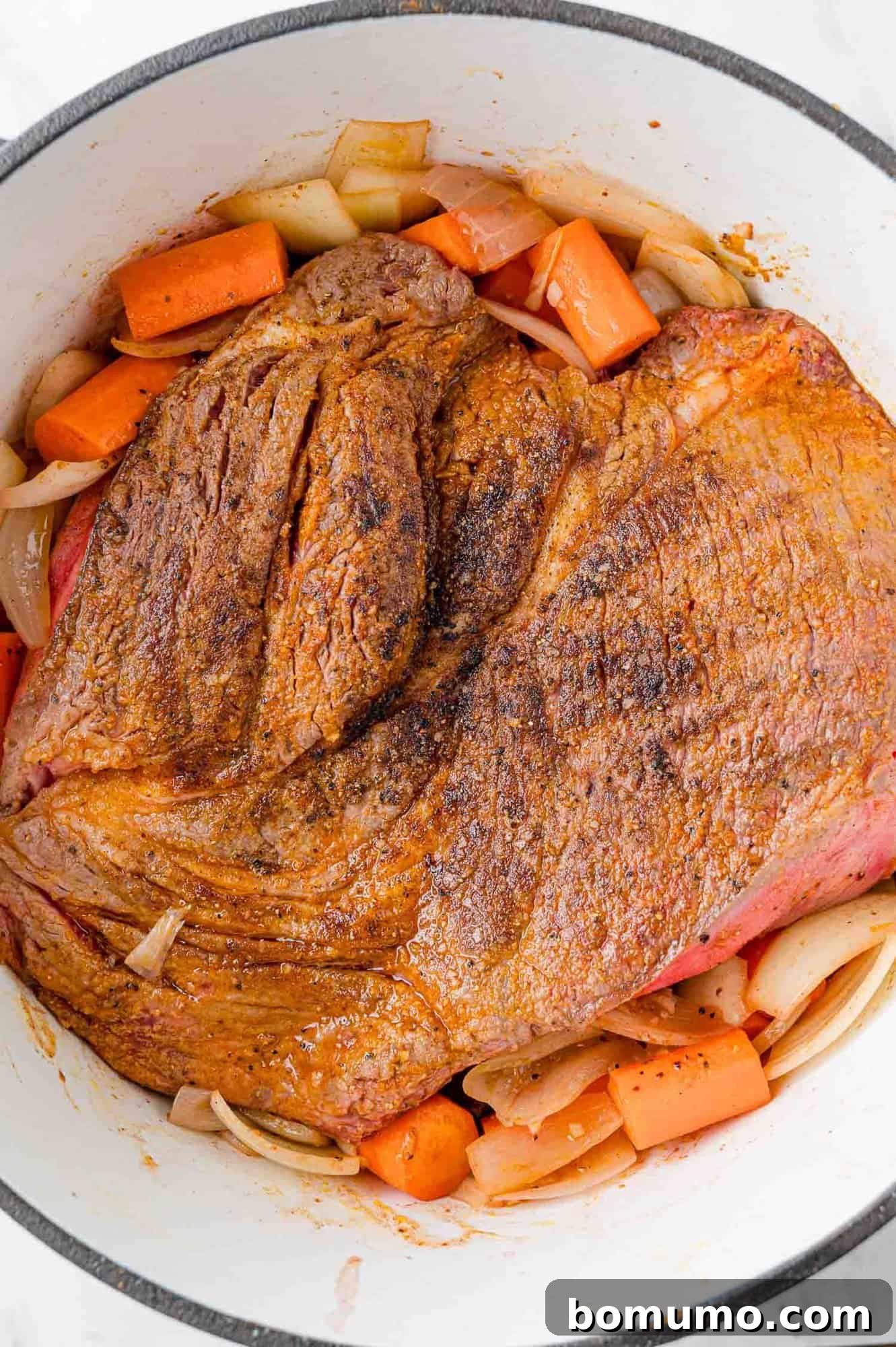 Browned pot roast added to pan with carrots and onions.