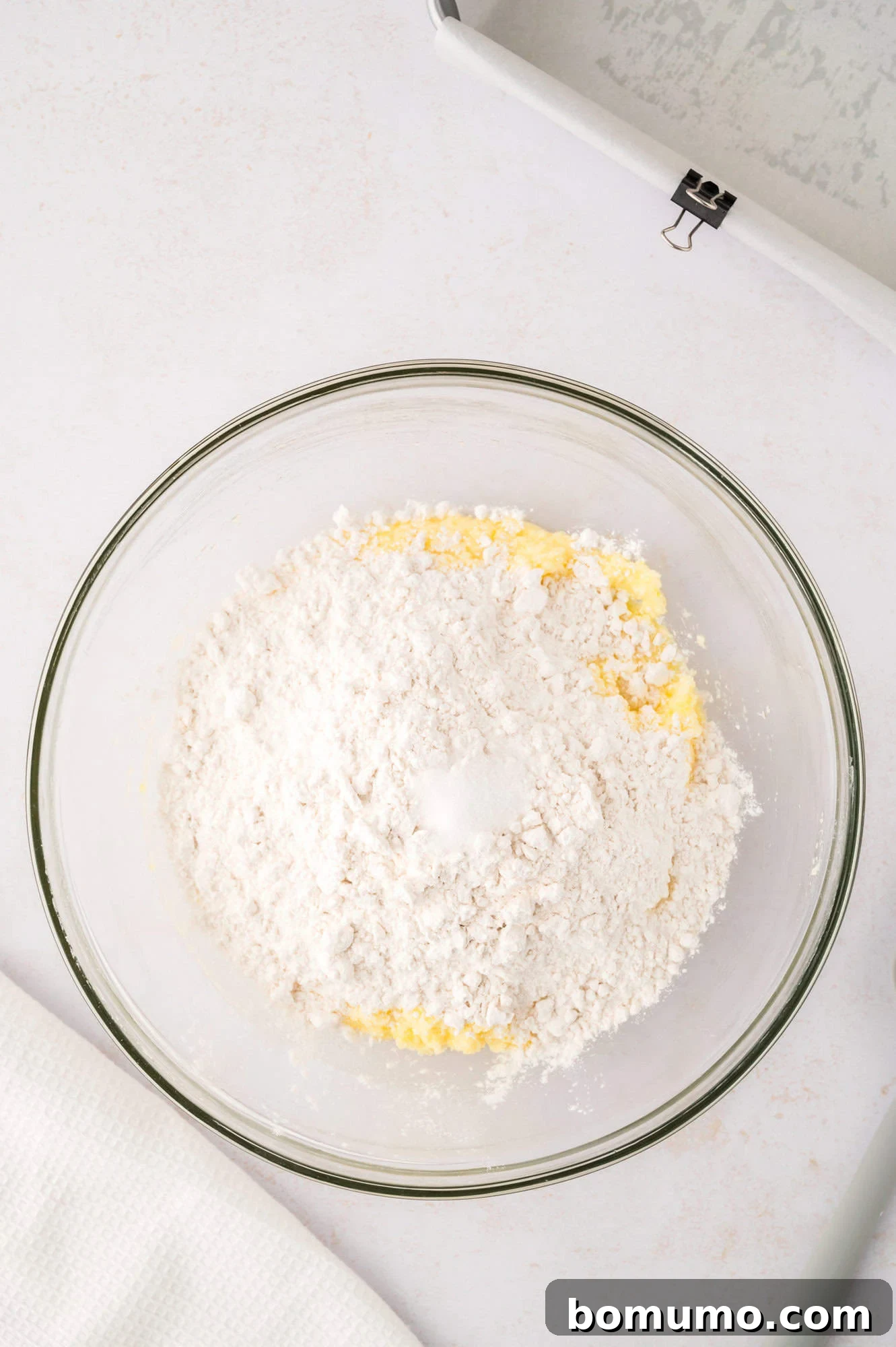 Dry ingredients (flour and salt) added on top of the wet lemon mixture in a bowl.