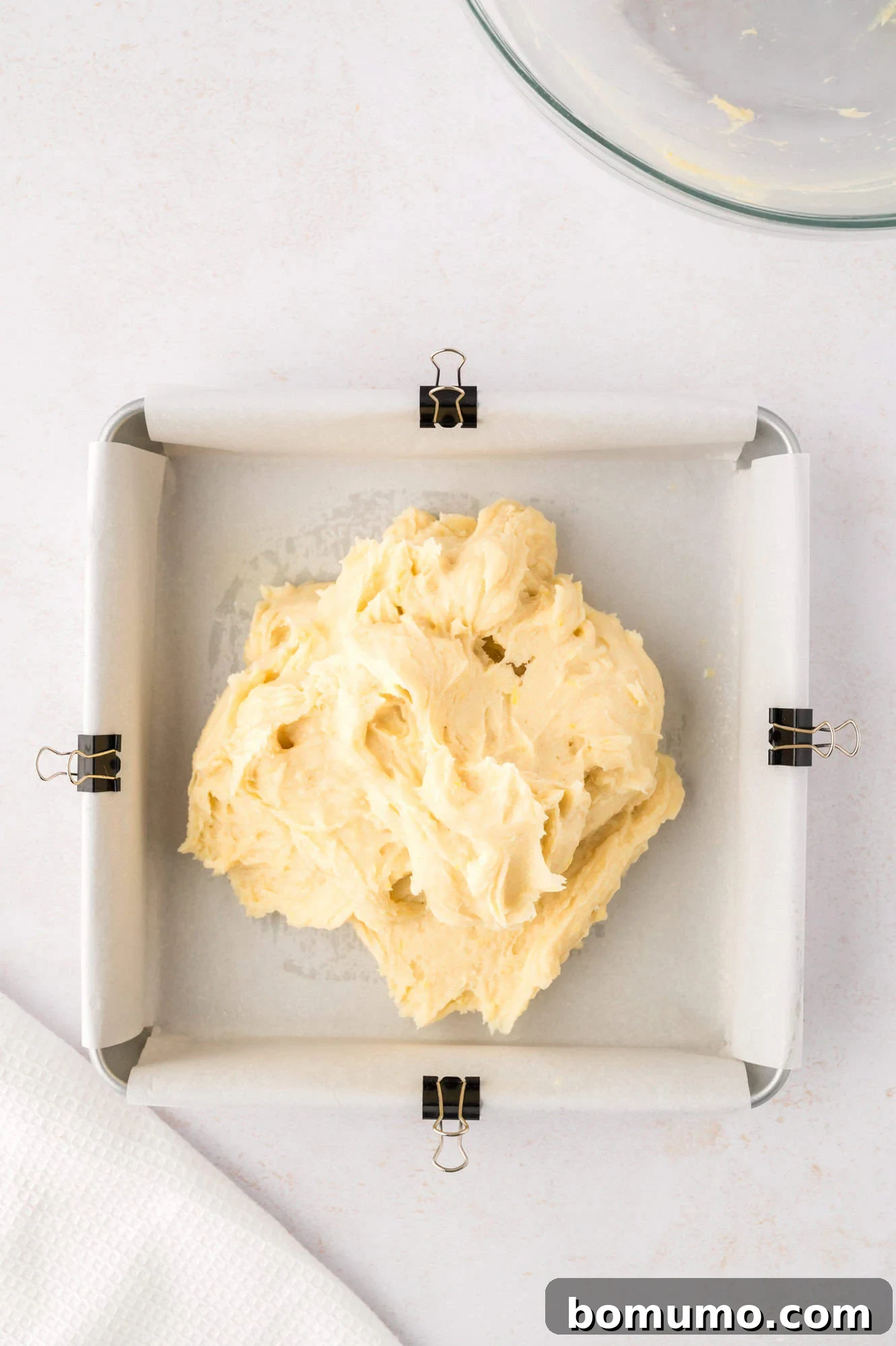 Thick lemon brownie batter scooped into the prepared pan, not yet spread evenly.