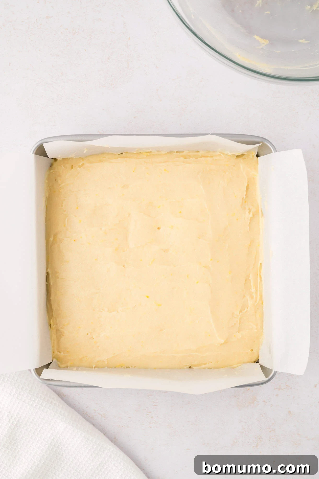 Unbaked lemon brownie batter spread smoothly and evenly into the prepared pan, ready for the oven.