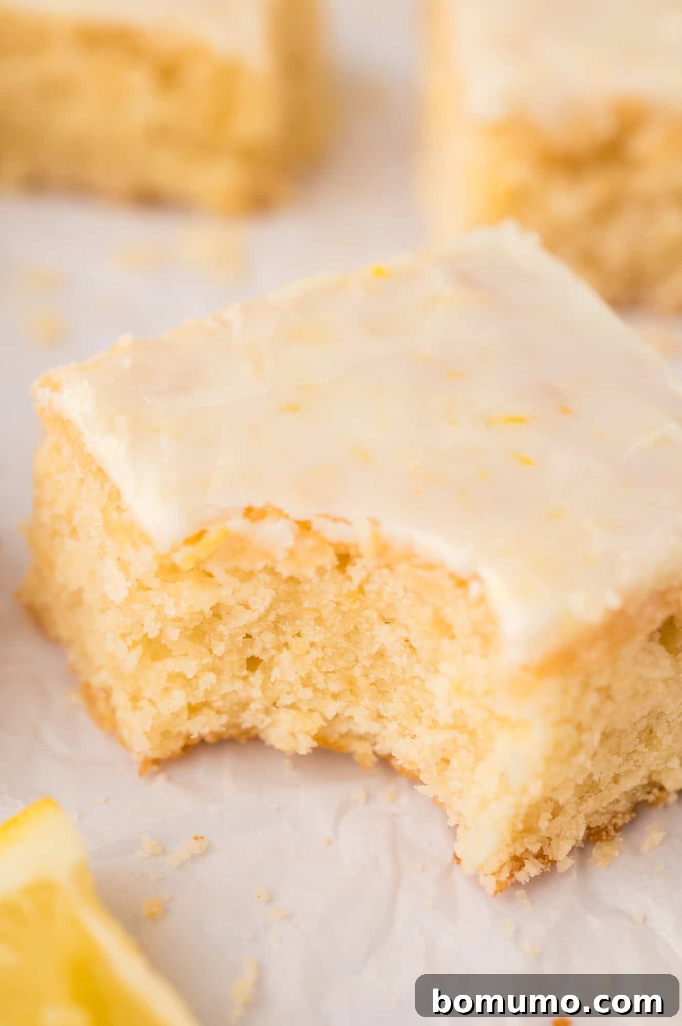 Close up image of a lemon brownie with a large bite taken from it, showing its dense, fudgy interior.