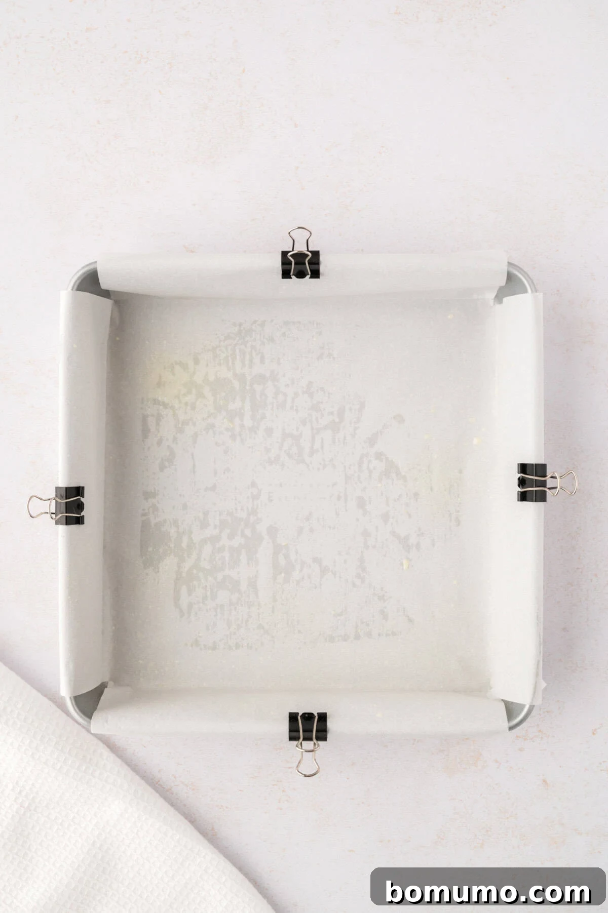 Parchment paper carefully added to the baking dish, secured with binder clips on the edges.
