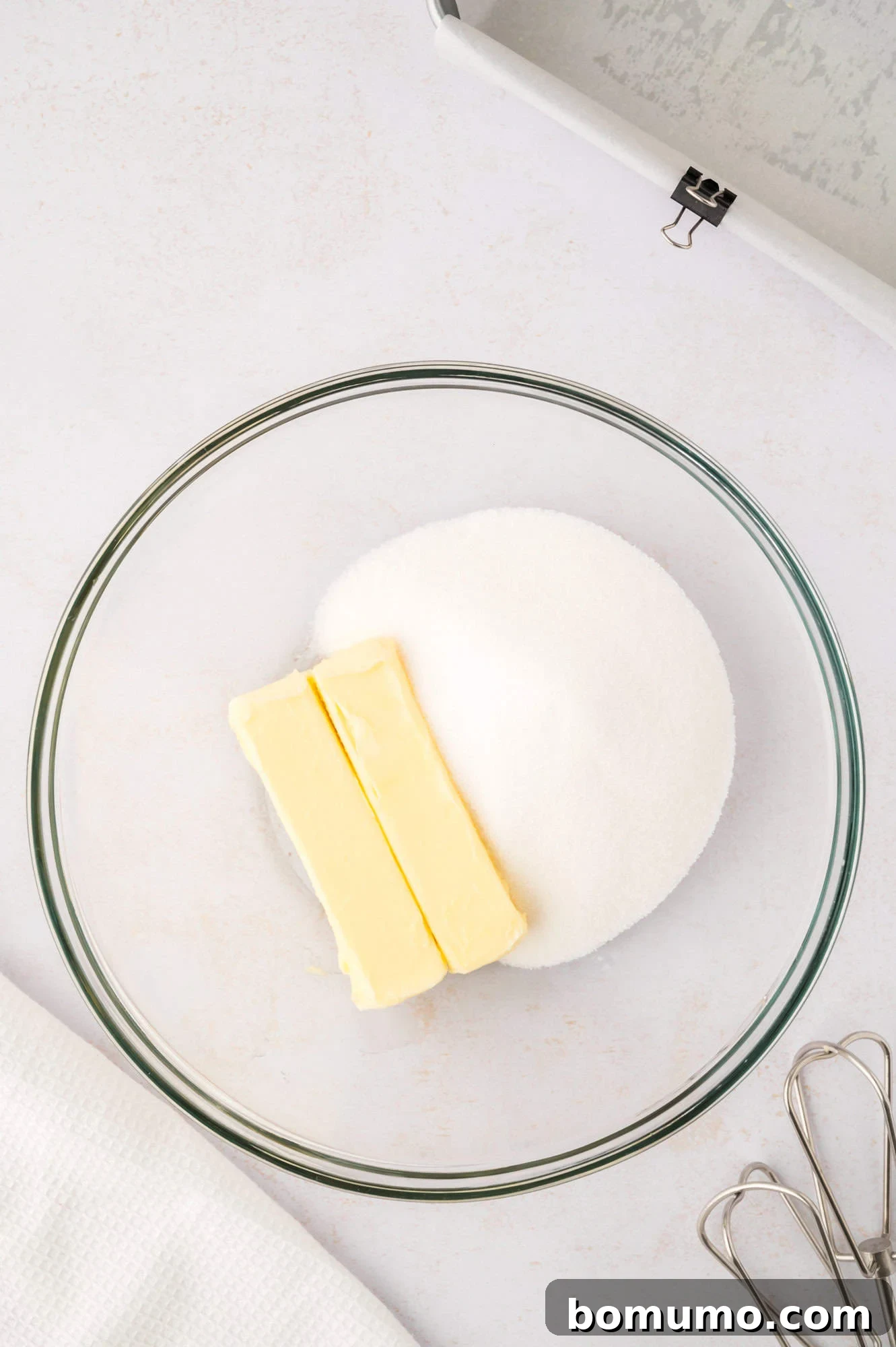 Unblended butter and sugar in a clear mixing bowl, ready for creaming.