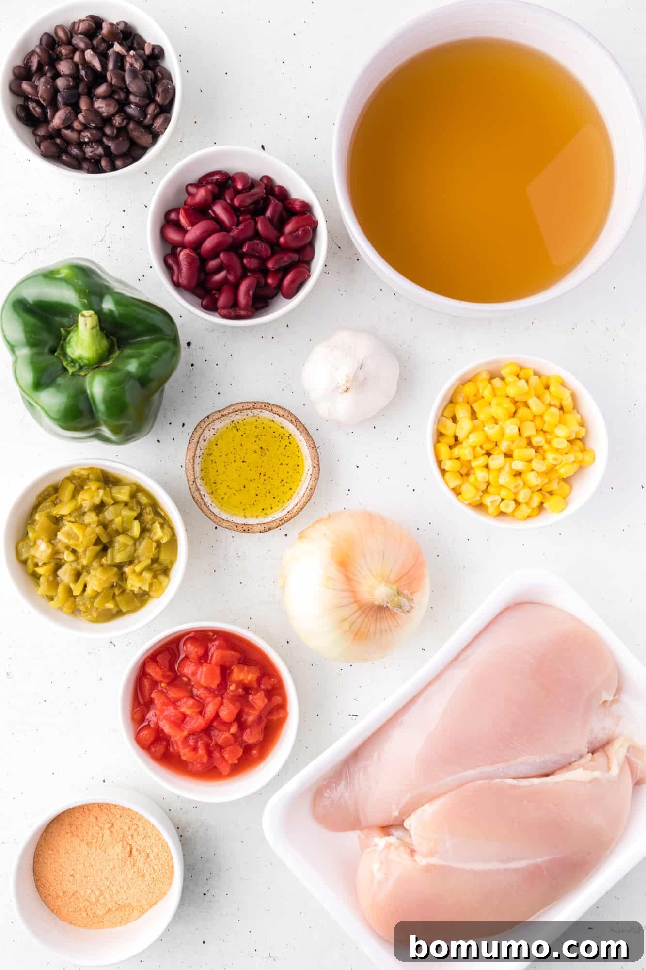 A flat lay photograph showcasing all the fresh and canned ingredients for chicken taco soup, neatly arranged on a countertop.
