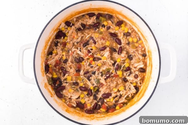 The shredded chicken fully combined with the rich, simmering taco soup, ready for serving.