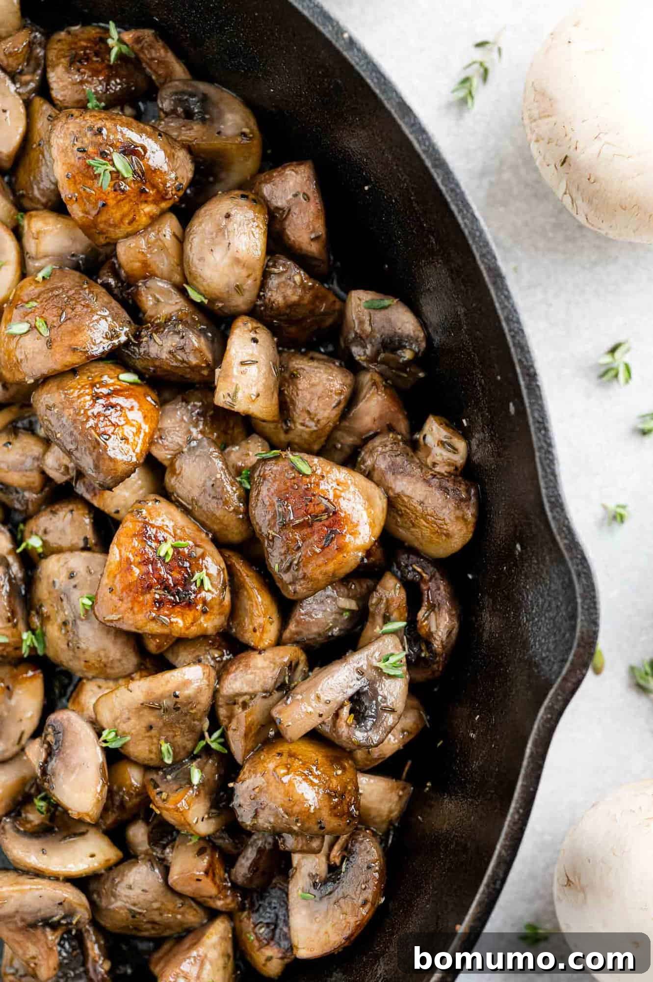 Perfectly browned, glistening mushrooms cooked to perfection in a black cast iron skillet, ready to be served.