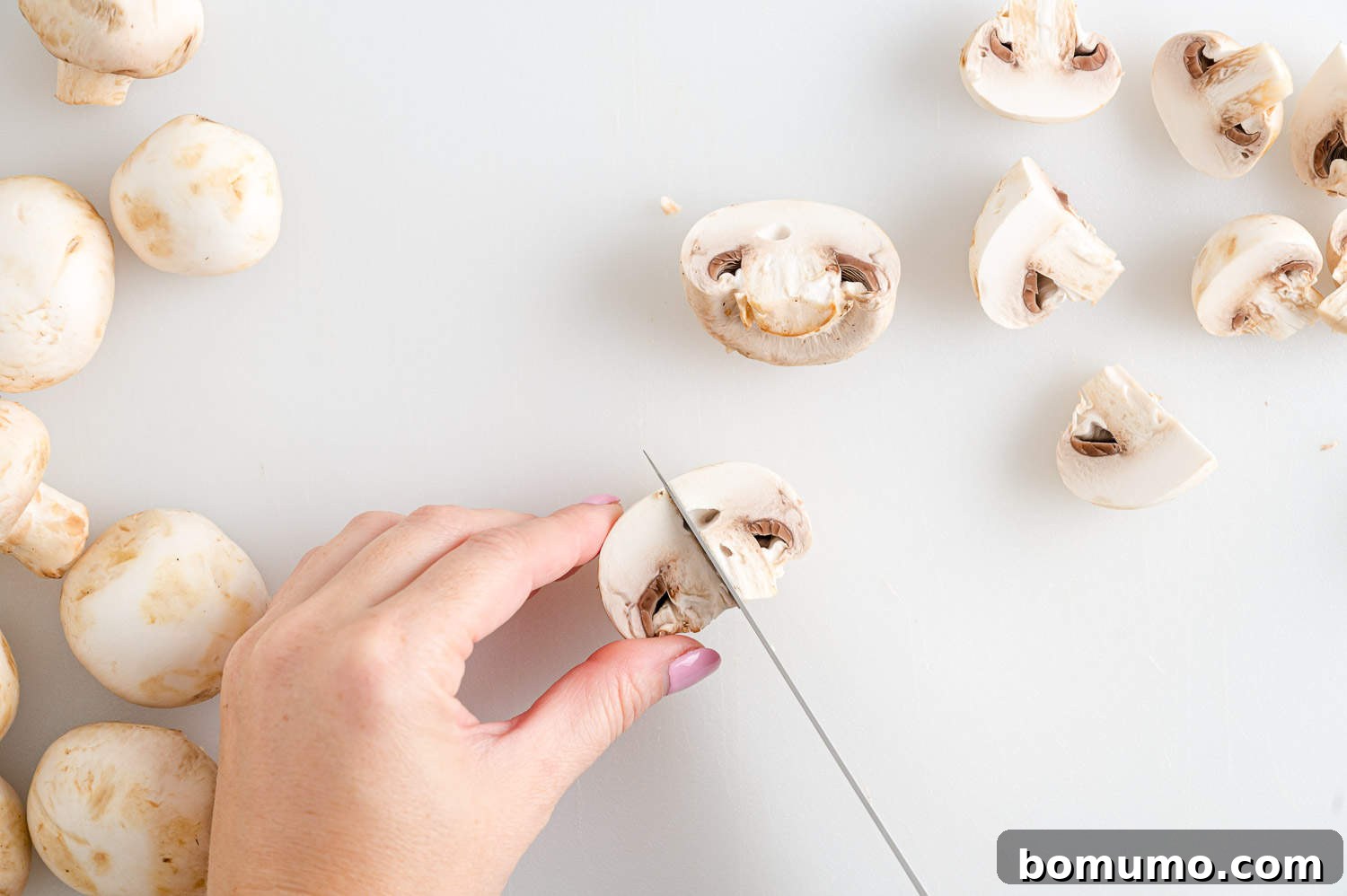 Mushrooms being expertly sliced on a cutting board, illustrating the preparation stage of the recipe.