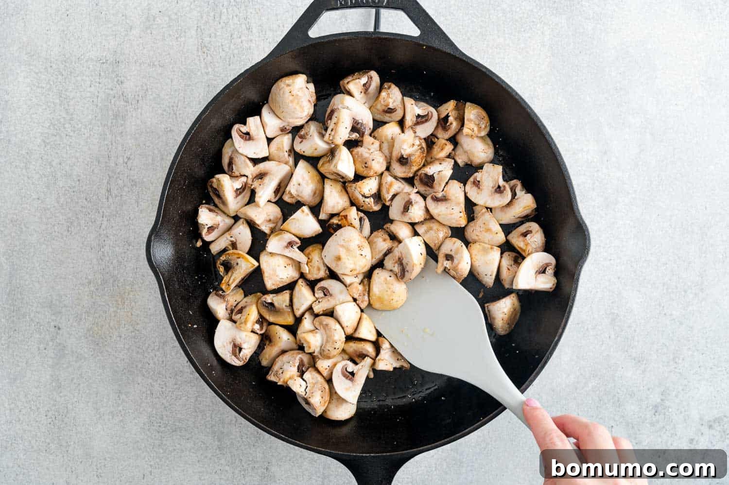 Uncooked mushrooms spread evenly in a black pan, illustrating the importance of a single layer for proper sautéing.