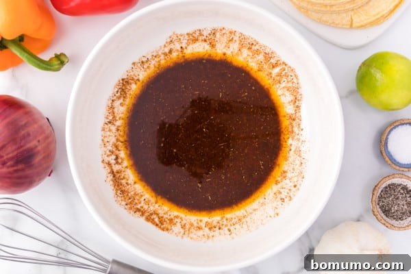 A small white ceramic bowl filled with a rich, dark, and aromatic steak fajitas marinade, showcasing its vibrant color and inviting texture, all ready for the meat preparation.
