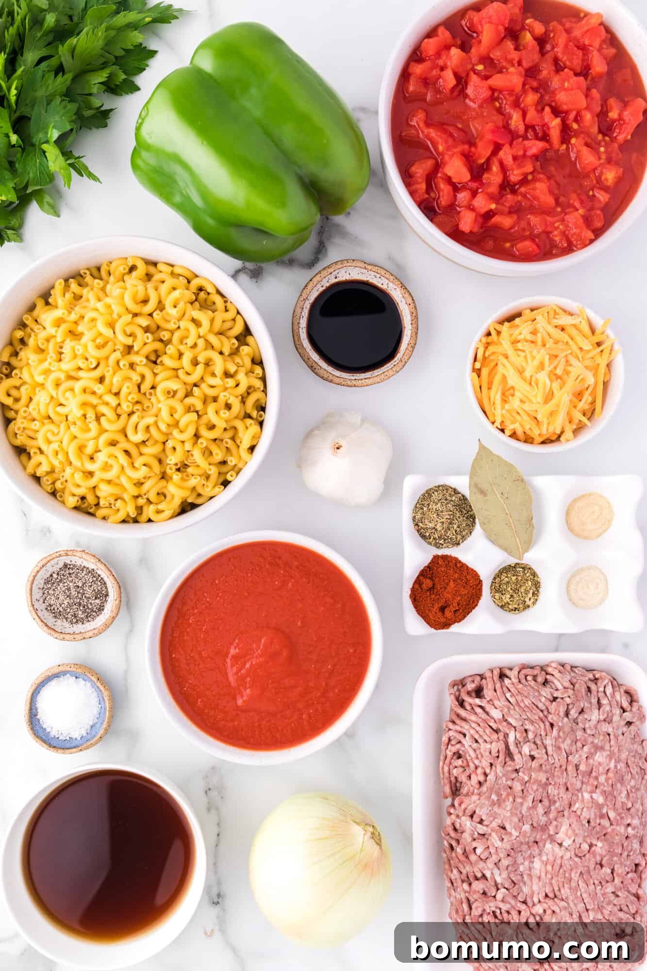 A selection of fresh ingredients laid out for making crockpot goulash, including ground beef, diced vegetables, and various spices.