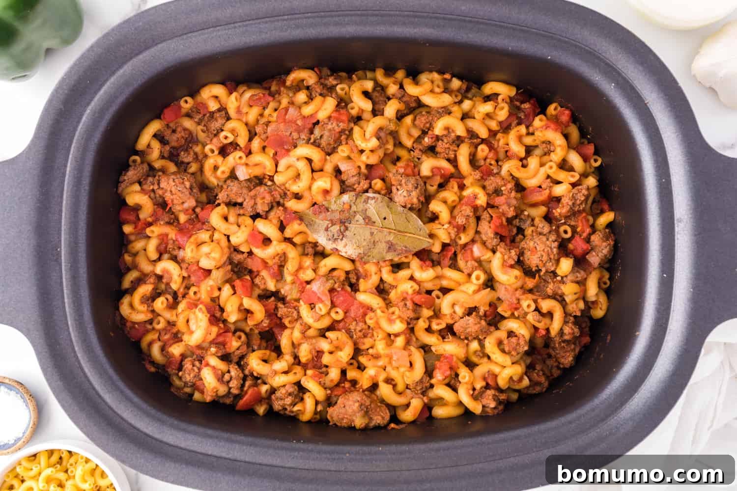 Overhead view of finished American goulash simmering inside the crockpot, rich with sauce and pasta.