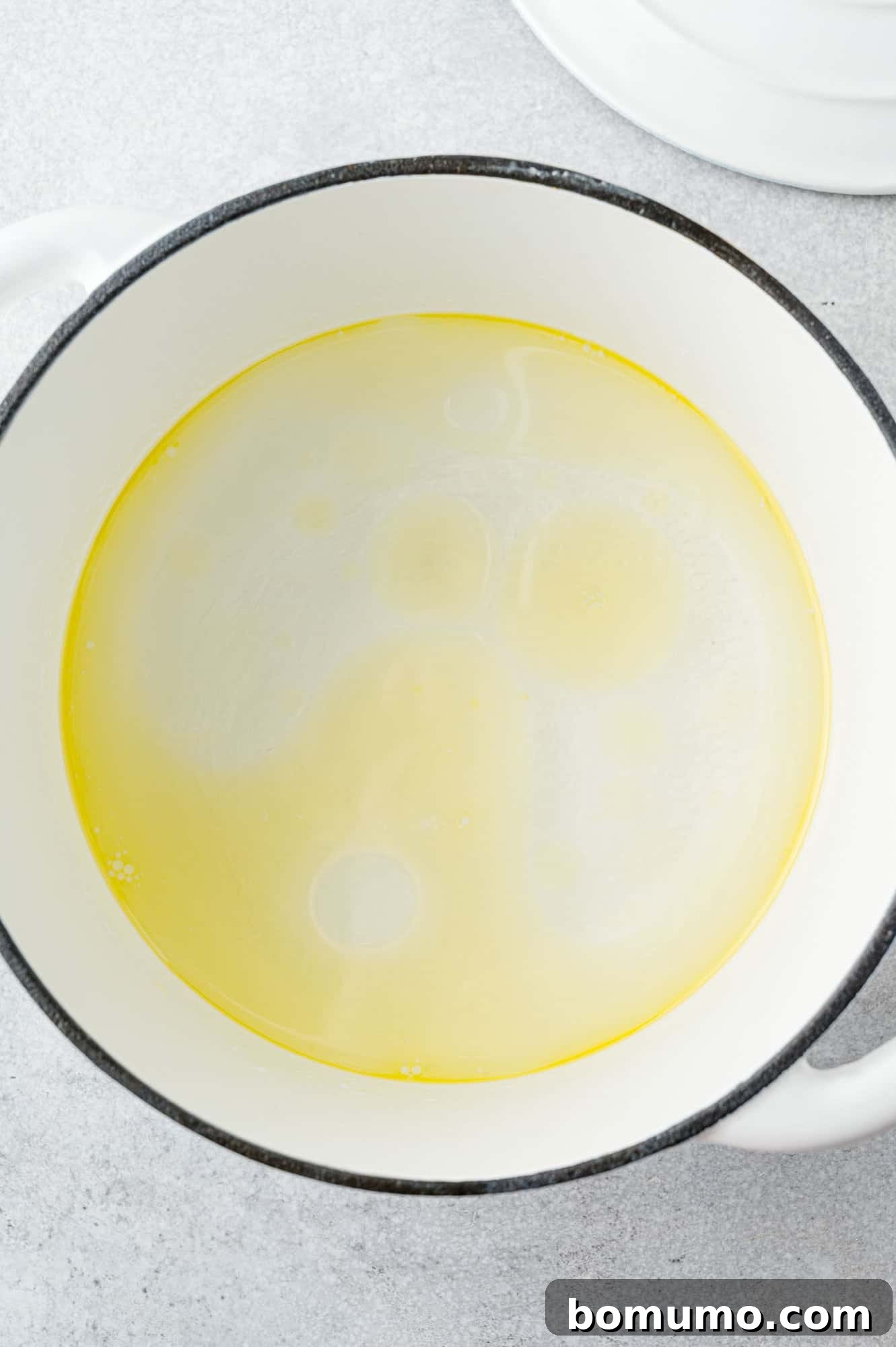 Oil and water simmering in a large pan before rice is added.