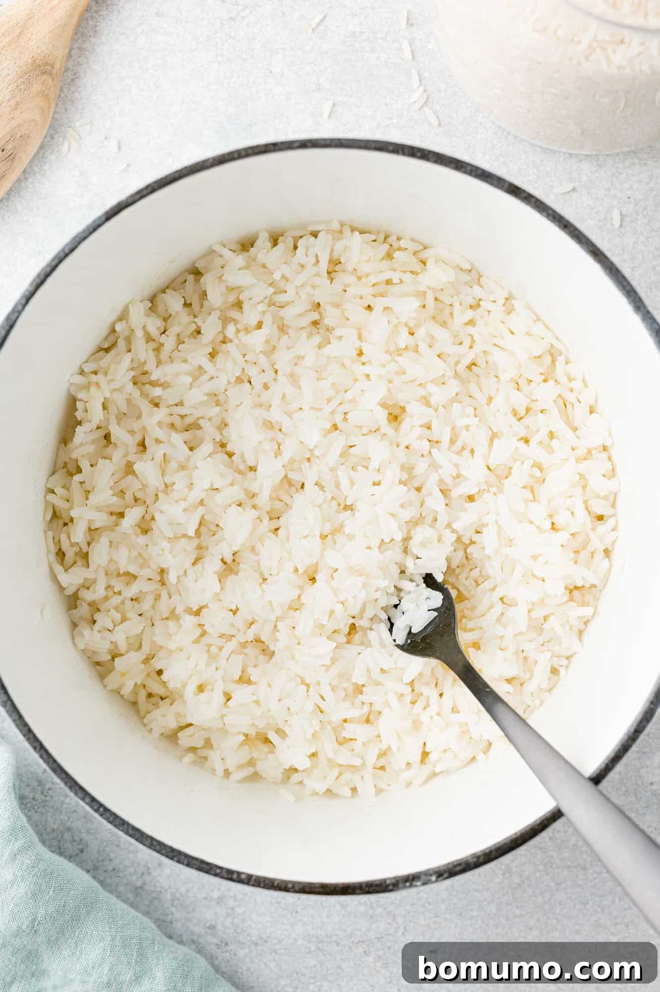 Perfectly cooked jasmine rice in a pan, being gently fluffed with a fork.
