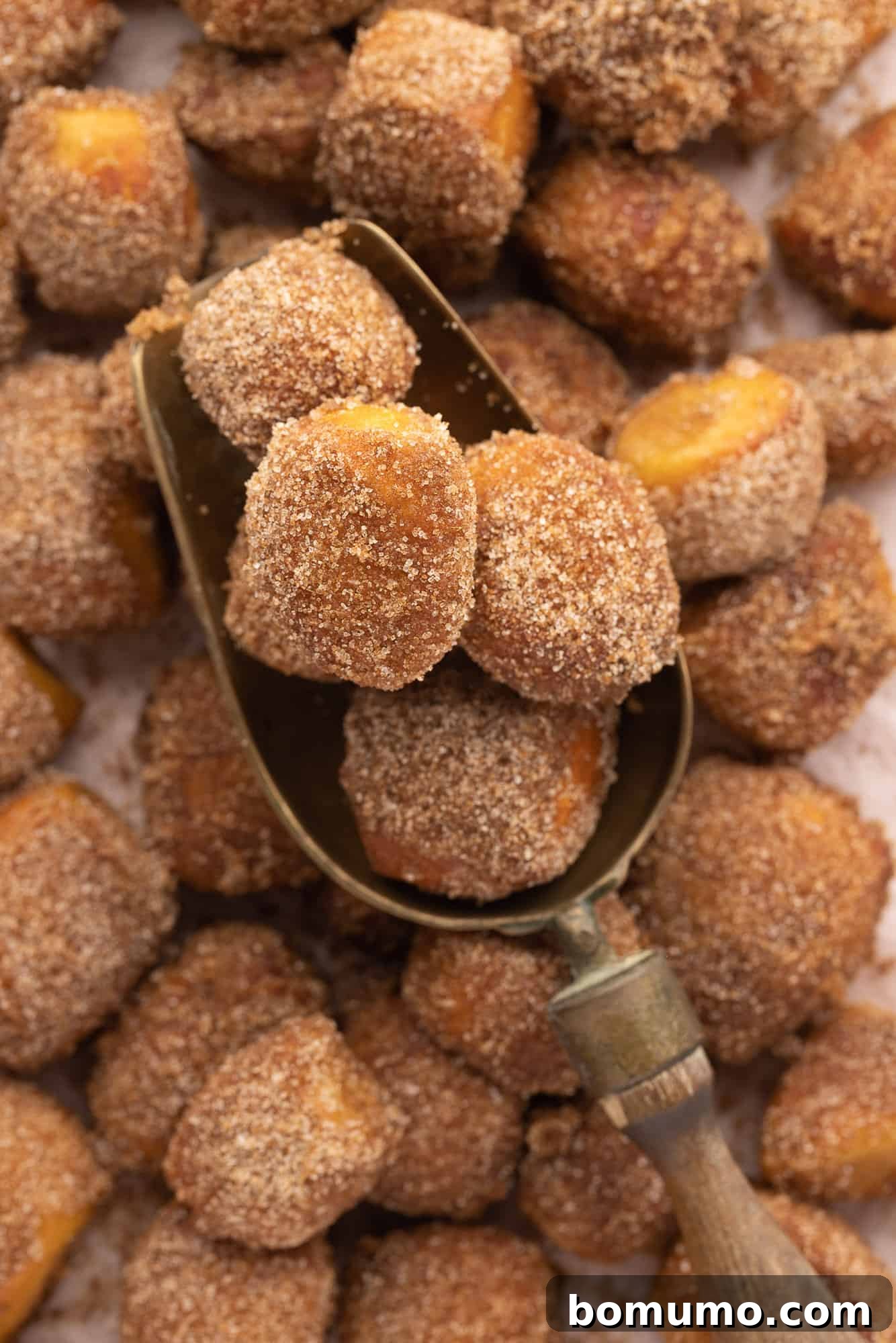 Close up of a scoop of cinnamon sugar pretzel bites resting on a pile of more pretzel bites.