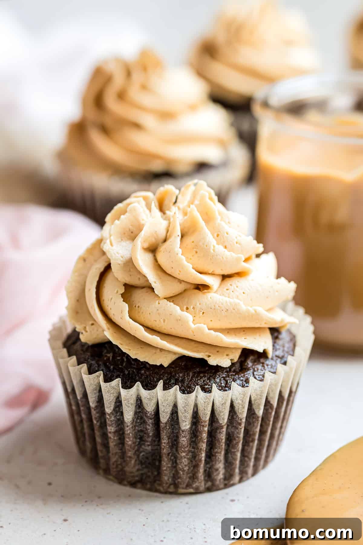 Peanut butter frosting beautifully piped on a rich chocolate cupcake, garnished with finely chopped peanuts.