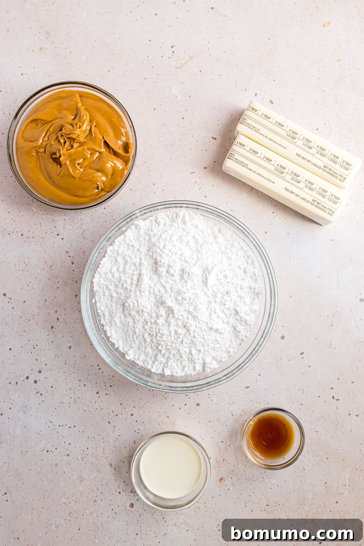 All essential ingredients for peanut butter frosting neatly laid out, featuring creamy peanut butter, unsalted butter, powdered sugar, and vanilla extract.
