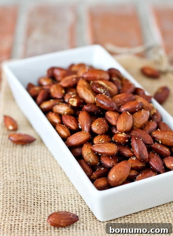 A bowl of freshly roasted almonds seasoned with olive oil and rosemary, ready to be enjoyed as a healthy snack.