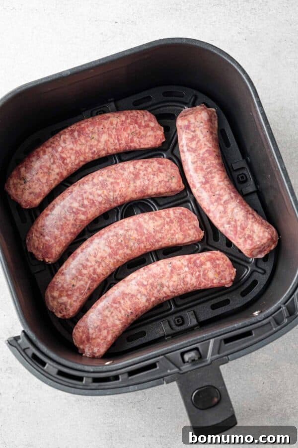 Uncooked Italian sausage in an air fryer basket.