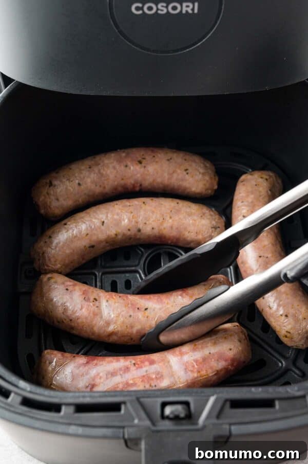 Sausages inside an air fryer basket, being flipped over.