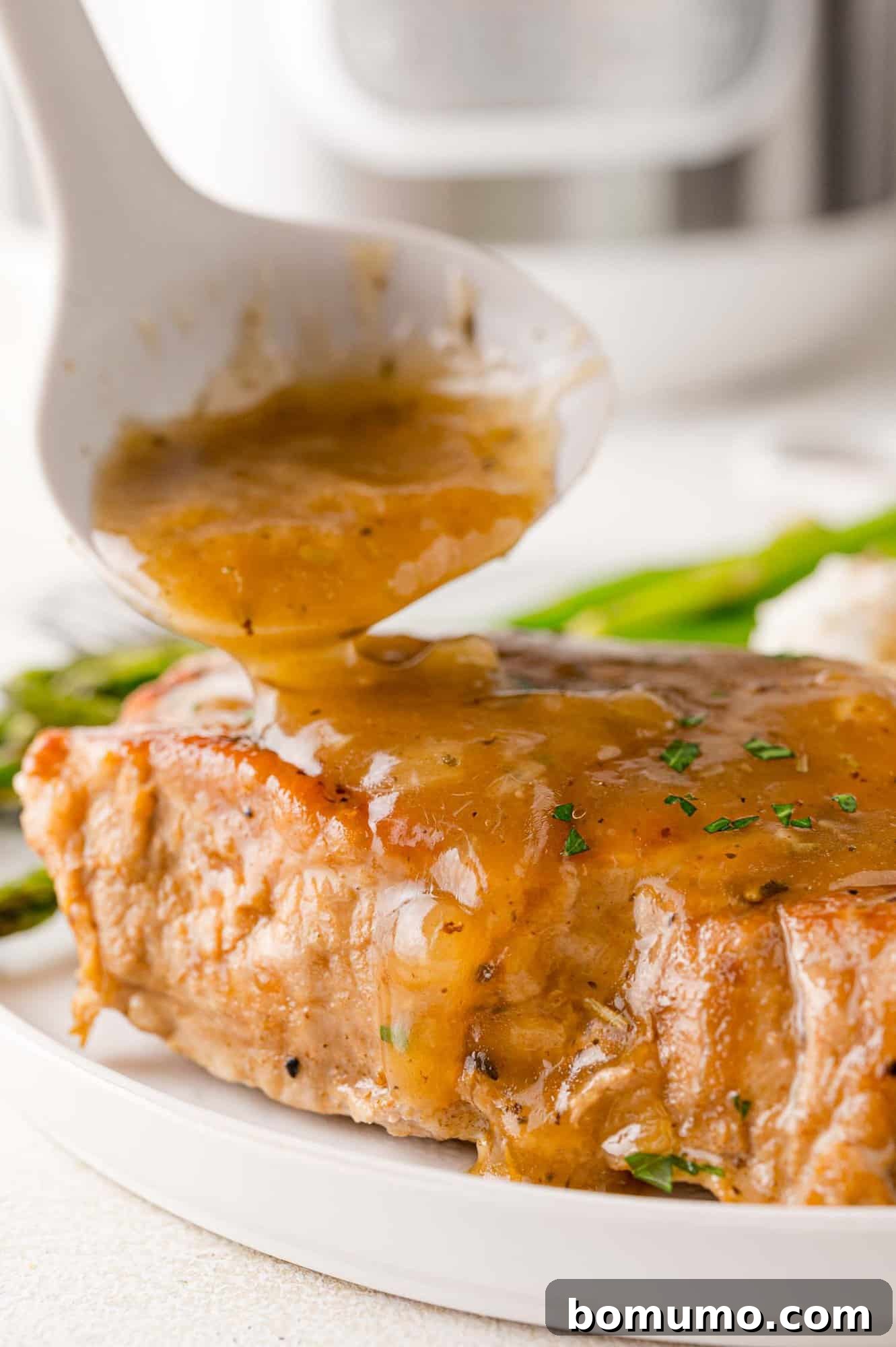 Gravy being poured on pork chop.