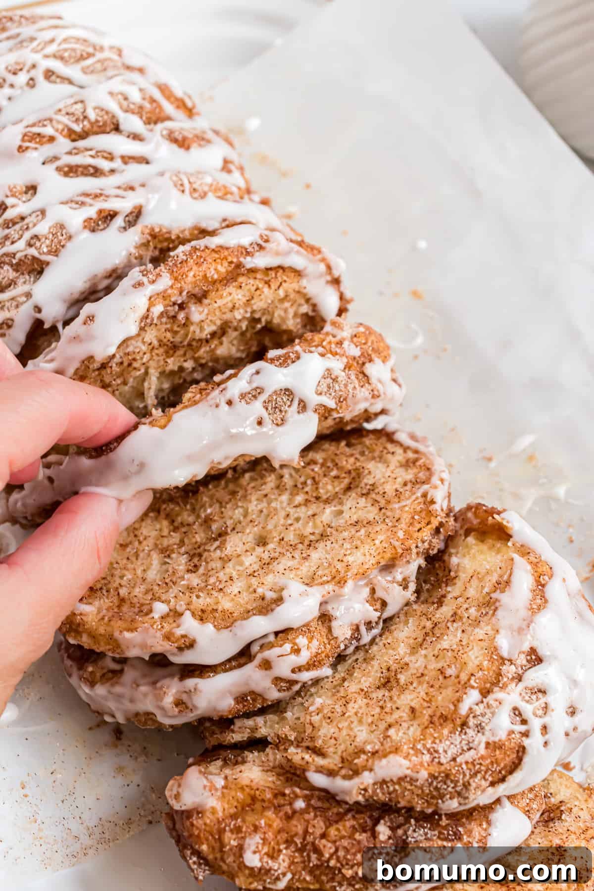 Hand in shot, pulling off a piece of cinnamon sugar pull apart bread.