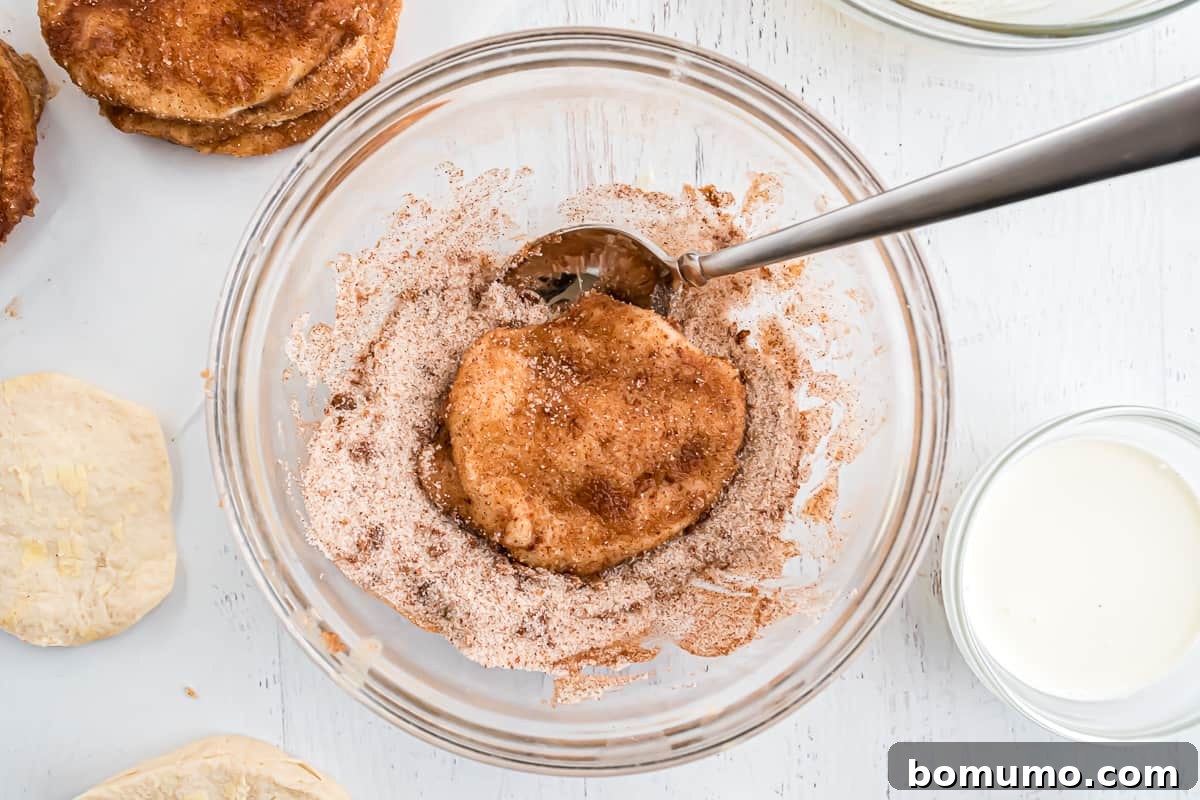 Biscuit being coated in cinnamon sugar mixture.