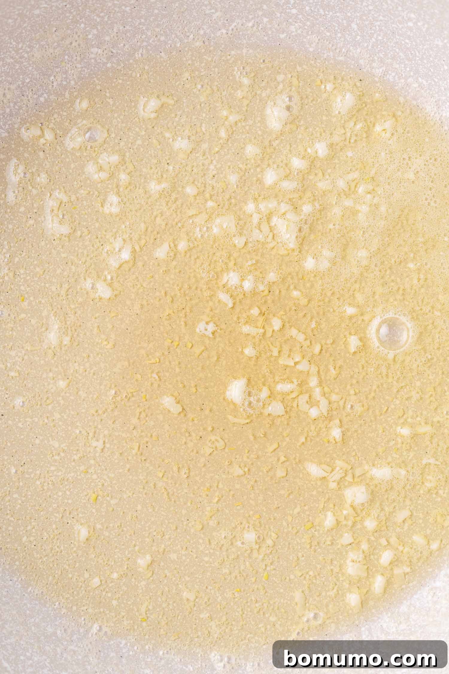 Chopped garlic sizzling in oil in a pan.