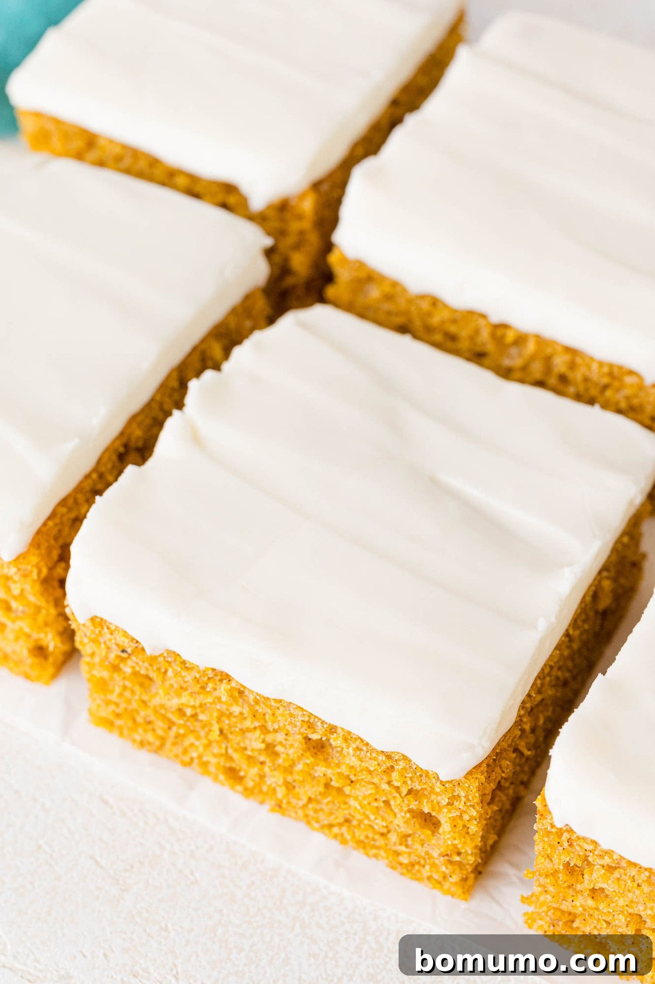 Autumn Pumpkin Spice Bars 2 Exquisitely frosted pumpkin bars, precisely cut into perfect squares, ready to be served as a delightful autumn treat.