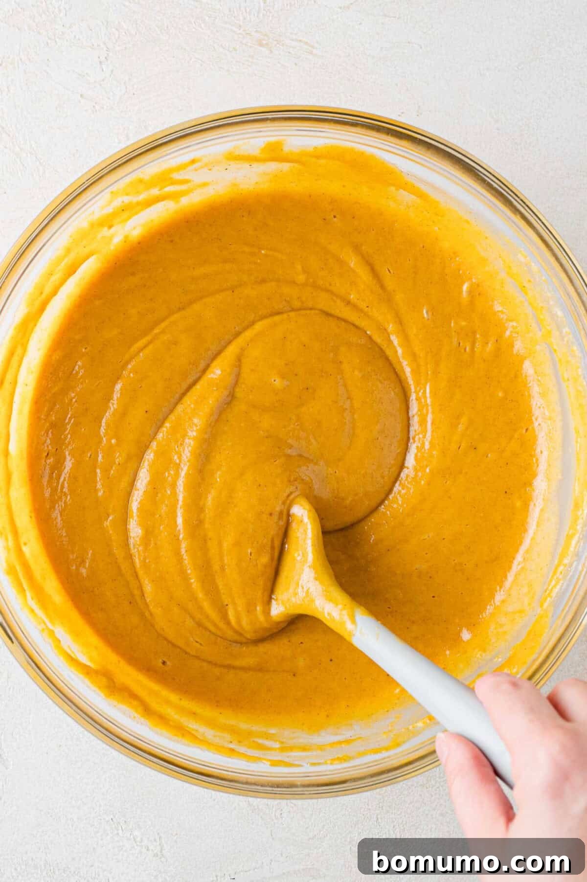 Autumn Pumpkin Spice Bars 11 A spatula gently folding the combined wet and dry ingredients, forming a perfectly blended pumpkin bar batter with a smooth consistency.