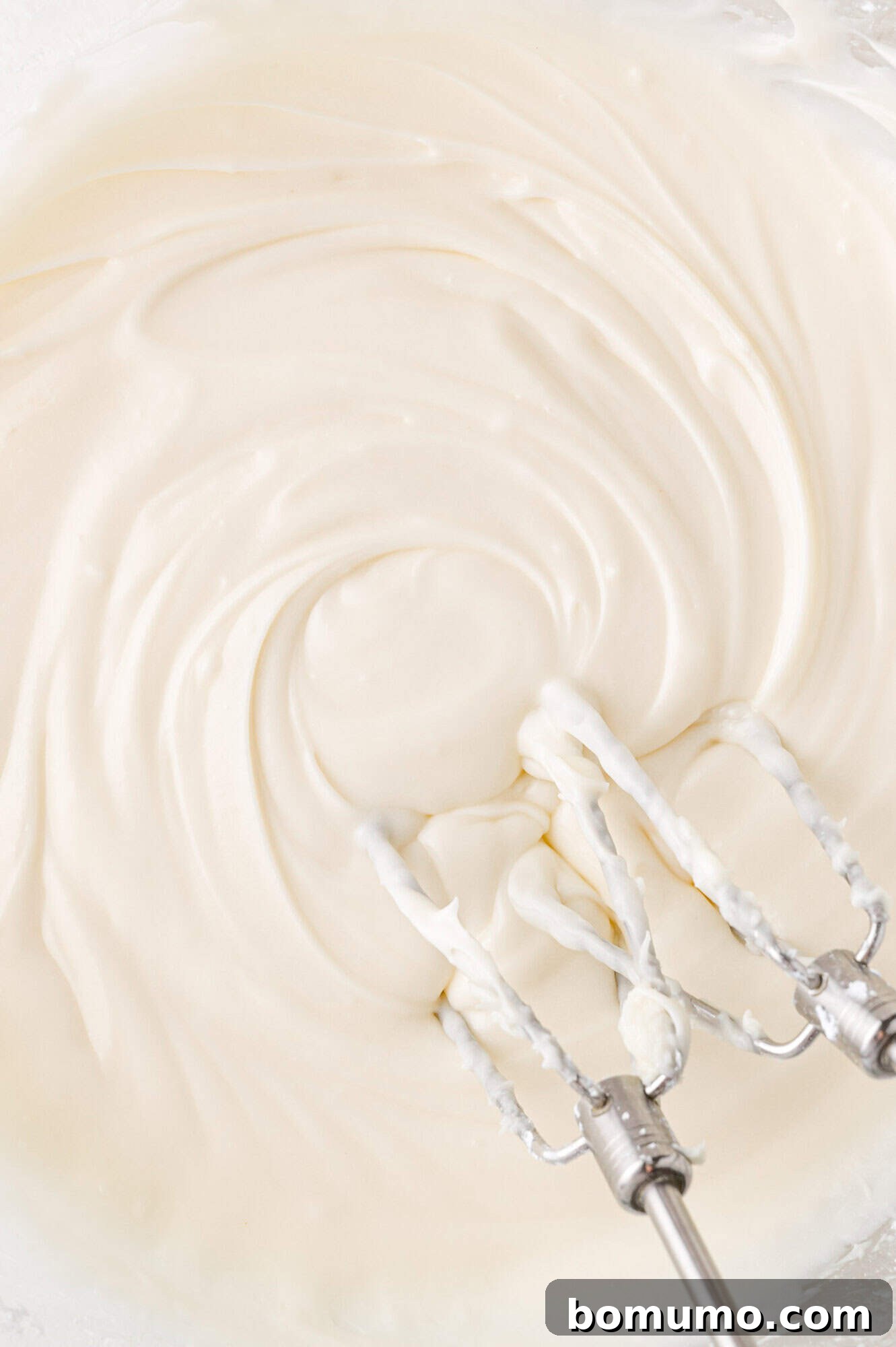 Autumn Pumpkin Spice Bars 15 The exquisitely prepared cream cheese frosting, showcasing its light, fluffy, and smooth texture, with electric mixer beaters still nestled in the bowl, ready for application.