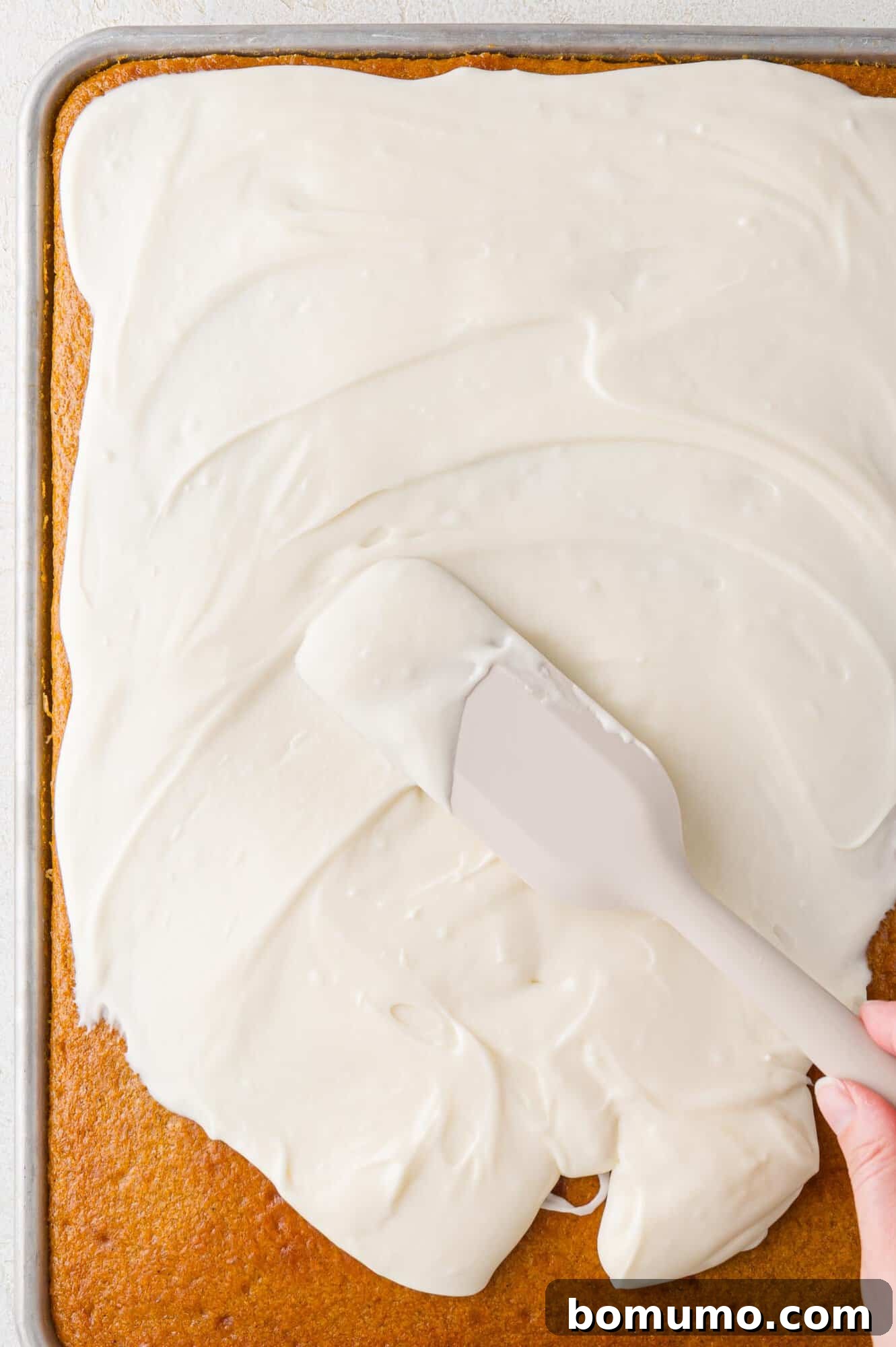 Autumn Pumpkin Spice Bars 16 Smooth, creamy cream cheese frosting being generously and evenly spread over the cooled pumpkin bars, creating an inviting and delicious top layer.