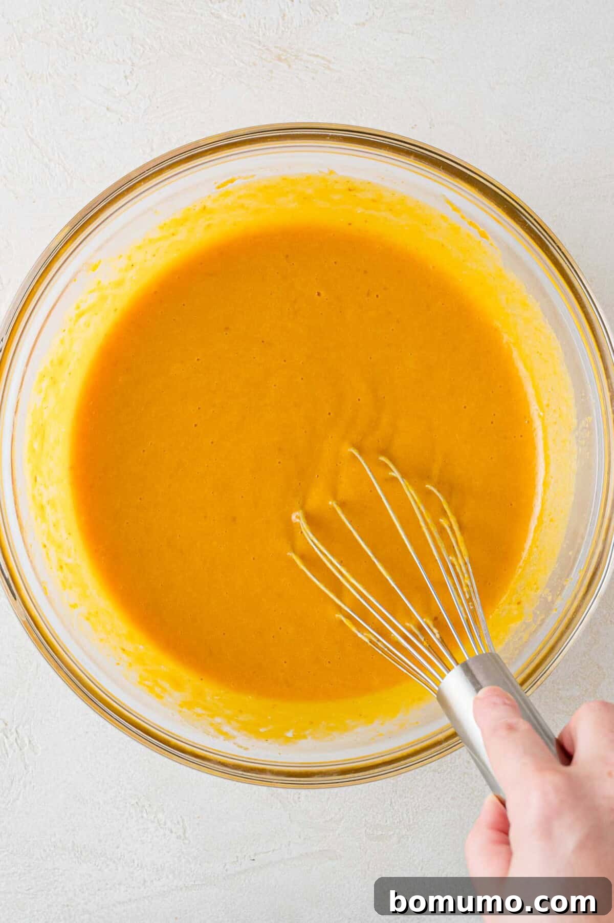 Autumn Pumpkin Spice Bars 7 The wet ingredients, a harmonious blend of pumpkin, yogurt, eggs, and vanilla, being smoothly incorporated in a mixing bowl with a whisk, forming a creamy base.