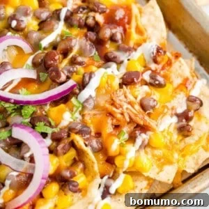 A square image of delicious BBQ Chicken Nachos with toppings, ready to eat.
