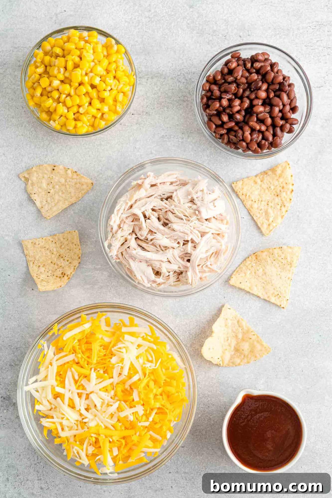 Backyard BBQ Chicken Nachos 4 All the fresh ingredients for BBQ Chicken Nachos laid out on a cutting board, including shredded chicken, cheese, corn, and black beans.