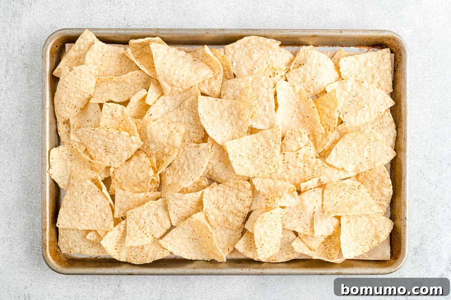 Backyard BBQ Chicken Nachos 6 A baking sheet filled with a uniform layer of tortilla chips, ready for toppings.