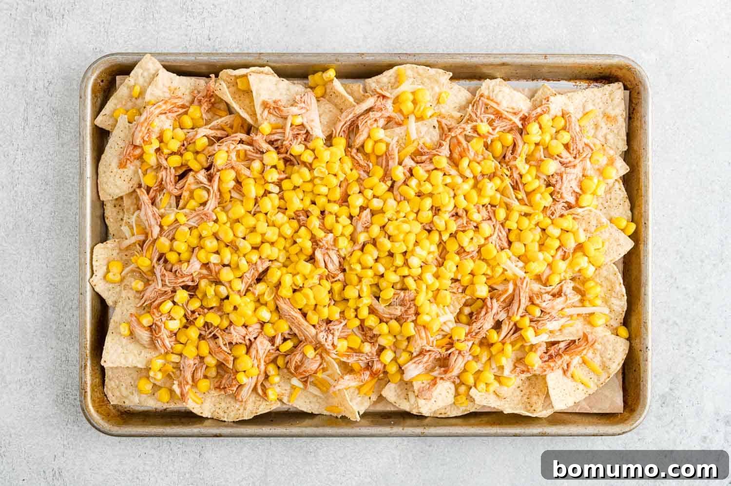 Backyard BBQ Chicken Nachos 10 Sweet corn kernels distributed over the BBQ chicken layer on the nachos.