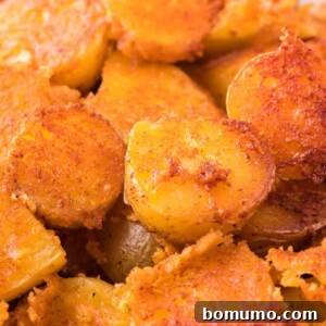 Close up of crispy parmesan potatoes in a white bowl.