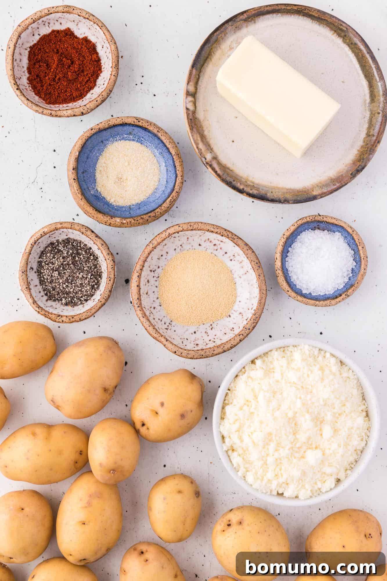 Ingredients for parmesan potatoes laid out on a white surface.