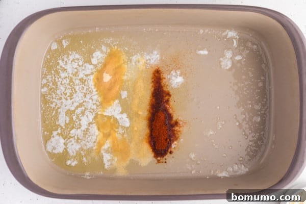 Seasonings added to melted butter in a baking dish, ready for mixing.
