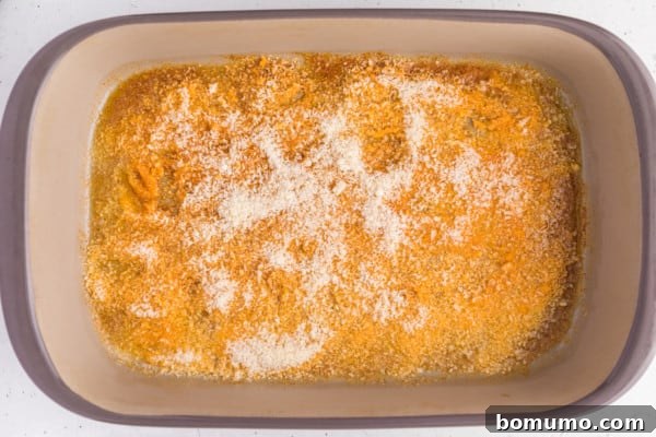 Parmesan cheese added on top of melted seasoned butter in a baking dish.