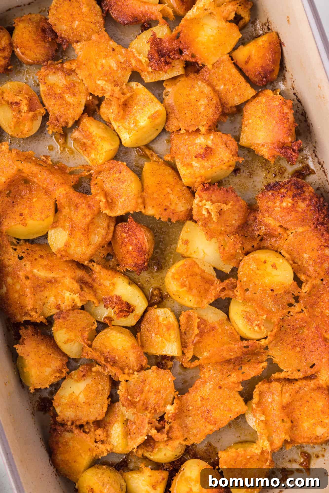 Overhead view of crispy parmesan potatoes in a baking dish, freshly roasted.
