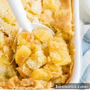Pineapple stuffing in a casserole dish with a spoon scooping a serving from the corner.