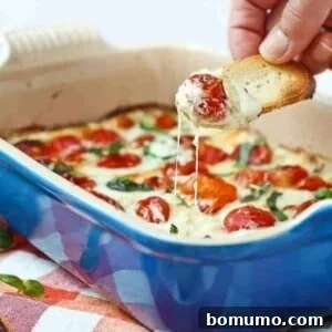 Piece of bread dipping into melted cheese and warm tomatoes.