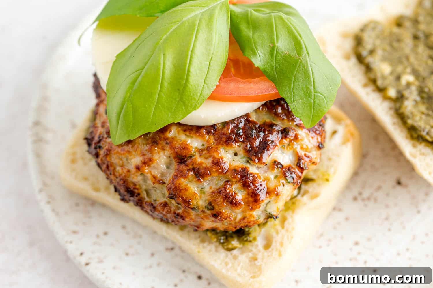 A fully assembled Caprese turkey burger, showcasing its fresh toppings and appetizing presentation.