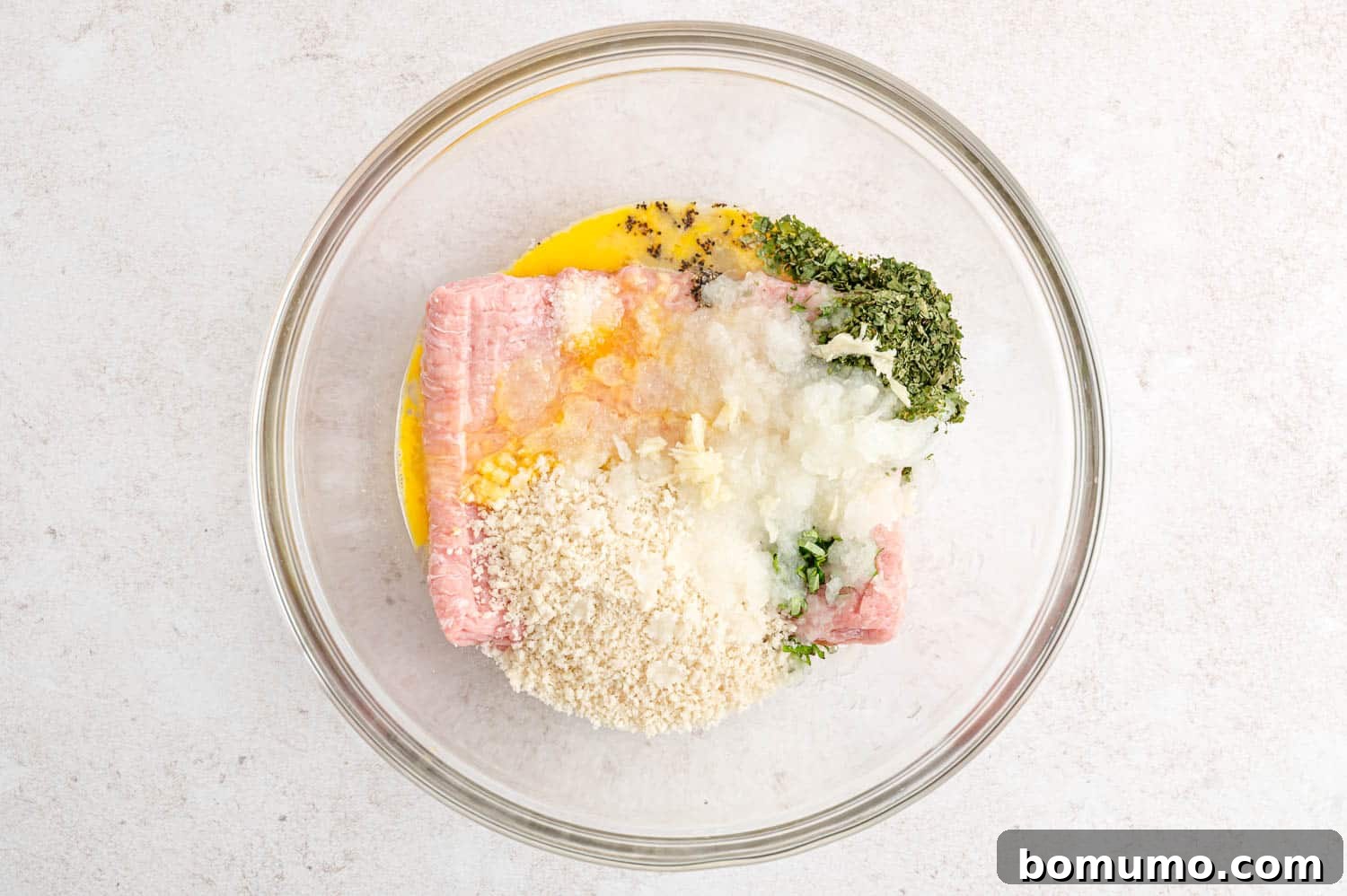A large mixing bowl containing all the raw ingredients for the turkey burgers, ready to be combined.