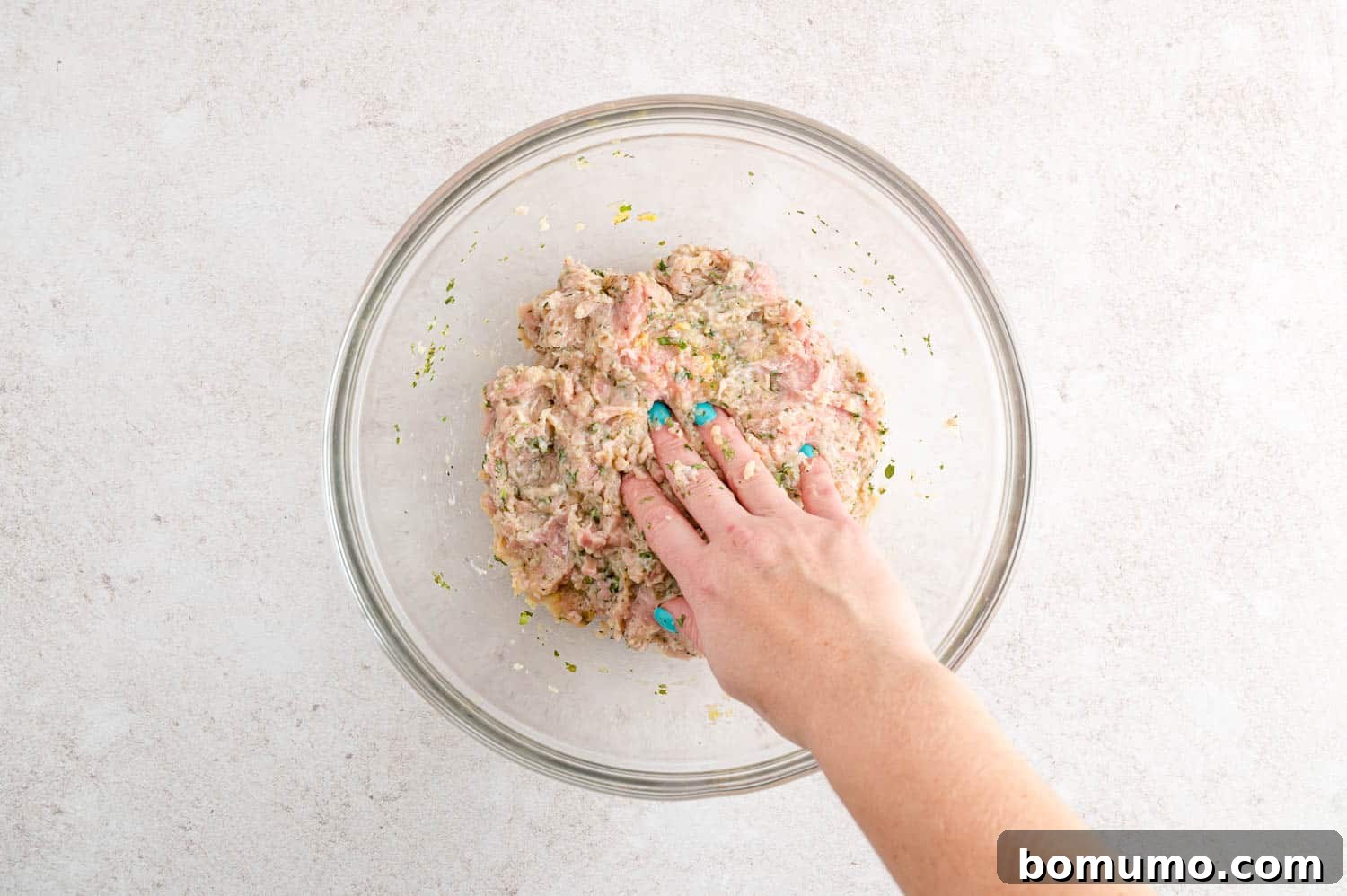 The ground turkey mixture, now fully combined with all seasonings, resting in a clear glass bowl.